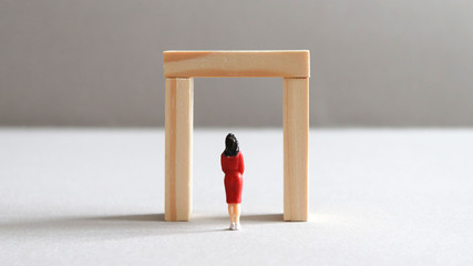 The back of a miniature woman standing in front of the small door.