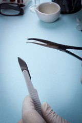 Hands in latex gloves with surgical instruments