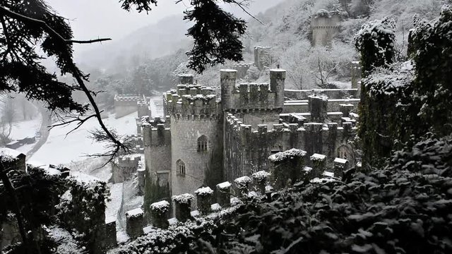 Magical European castle with gently falling snow, framed by trees, Welsh ruins, Gwrych castle in Abergele.