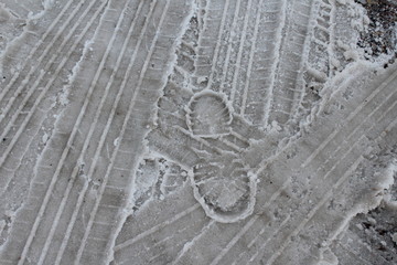 footprint in snow with tire tracks
