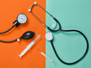 Medical equipment on a colored paper background. Stethoscope, syringe, thermometer, tonometer. Top view, flat lay..