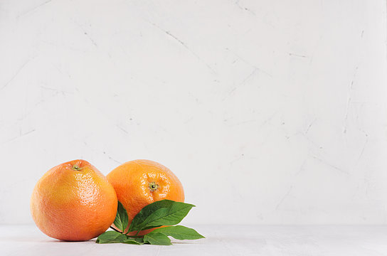 Two fresh glossy whole grapefruits on white wooden background with copy space.