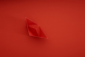 Red paper ship on red background