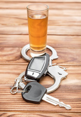  Alcoholic shot, handcuffs and car key on wooden table.