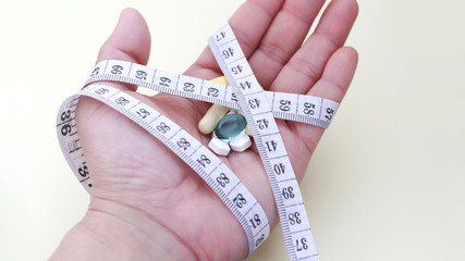 A tape measure around the palm and the pills on the palm.