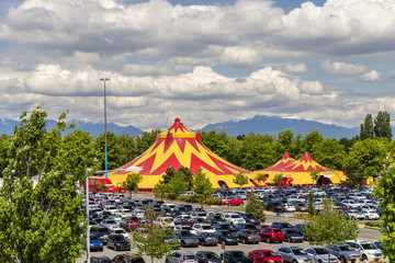 Domes of the tent of a traveling circus in the city, green trees and mountains