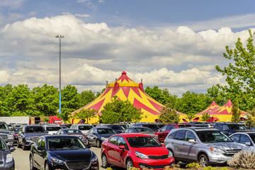 caravan circus in the city, green trees, cars in a parking lot