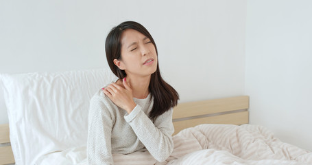 Woman feeling shoulder pain on bed