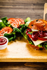 Tasty burger with vegetables on cutting board