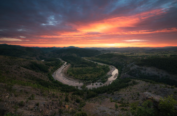 Fiery sunset over the river bend in the mountains