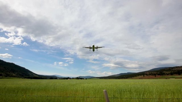 Small Air Plane Flying Over Large Farm Field Surrounded by Hills in BC, Canada
