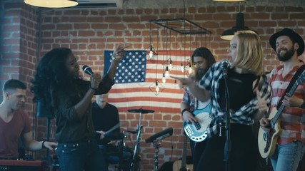 Young multiethnic singers showing new song having performance with musicians on stage looking super expressive