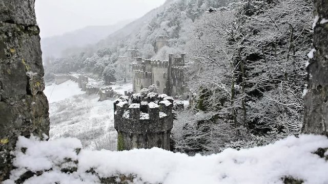 Gwrych castle Ruins framed by turret wall, British European castle Snowing gently, magical covered in snowy winter landscape