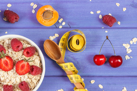 Oat flakes or oatmeal with fruits and tape measure with spoon, concept of slimming and healthy nutrition