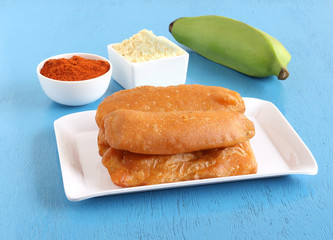 Raw banana bajji or fritter, a popular Indian vegetarian snack, with its main ingredients like raw banana, chickpea flour and chili powder.