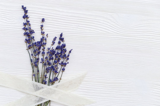 Delicate flowers of lavender with braid on white wooden background with copy space. View from above. Floral border with lavender.