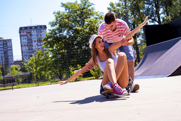 Happy young couple having fun with skateboard in the skate park