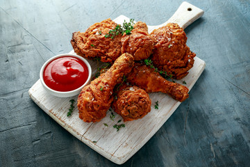 Fried crispy chicken legs, Thigh on white cutting board with ketchup and herbs