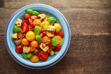 Panzanella Tomato salad with red, yellow, orange cherry tomatoes, capers, basil and ciabatta croutons. summer healthy food.