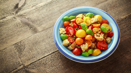 Panzanella Tomato salad with red, yellow, orange cherry tomatoes, capers, basil and ciabatta croutons. summer healthy food.