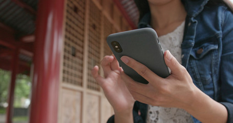 Woman using cellphone in Chinese garden