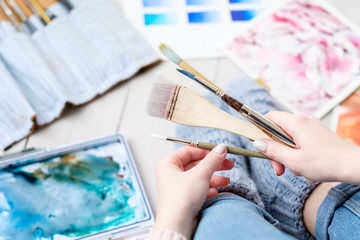 creative leisure. painting hobby. artful personality. painter holding brushes. watercolors and drawing scattered on the floor