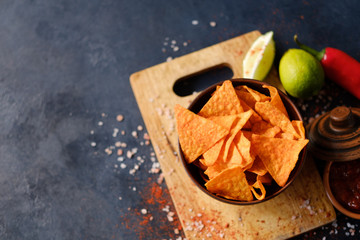 junk fast food and unhealthy eating. nacho tortilla chips in a bowl. crunchy triangular crisps on dark background