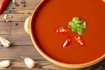 Spicy tomato soup on a wooden table, top view