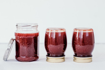 Preparing marmalade at home. Fresh red fruits from own garden or farmer market. Self supply, traditional canning with boiling in sugar. Filling glass jars with hot jam.