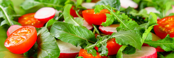 Vegetarian salad of arugula, tomato, radish and mozzarella cheese on an old wooden table.