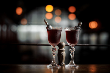 Two elegant glasses filled with fresh sweet and strong summer Arnaud cocktail on the dark blurred background