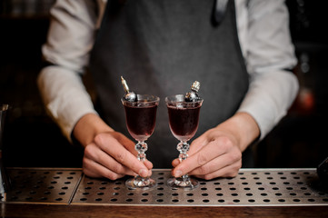 Bartender holding two elegant glasses filled with sweet summer Arnaud cocktail