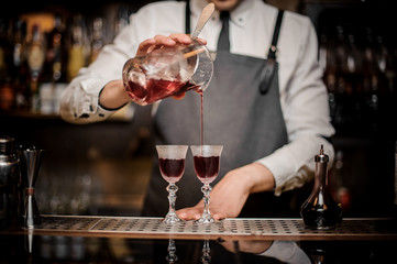 Bartender pouring strong summer Arnaud cocktail into the glasses