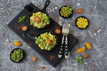 Scrambled eggs with green beans, corn, green peas and fresh Basil in portion a cast iron skillet
