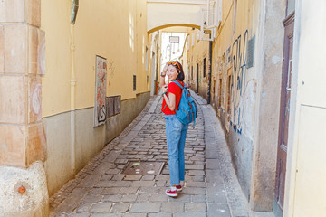 Woman tourist with a backpack travels through narrow European streets