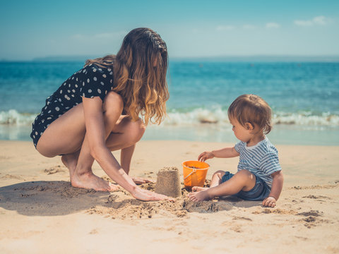 Young mother playing with son on beach