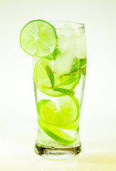 summer cold drink mojito lime and mint with ice and soda with drops on a glass on a white background