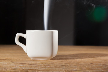 vapor  over a cup of morning breakfast on an oak table dark background