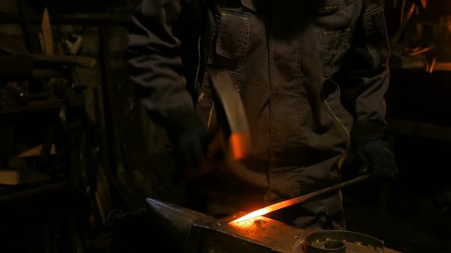 Professional blacksmith working with metal on anvil at forge, workshop. Handmade, craftsmanship and blacksmithing concept