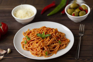 Spaghetti with tomato sauce in the dish on the wooden table
