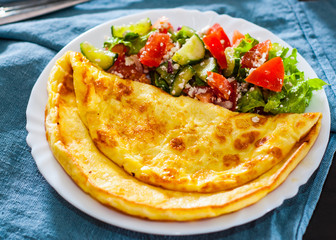 Omelet with vegetable salad in white plate on table