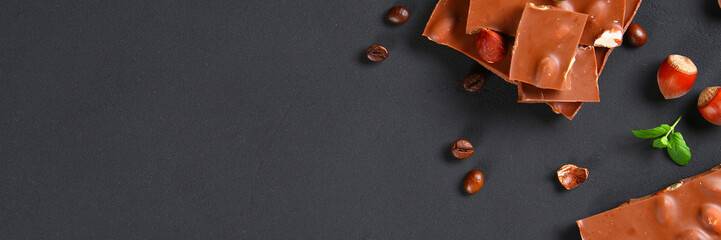 Chocolate with hazelnuts, mint and grains of coffee on a dark gray table. Top view. Copy space.
