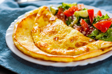 Omelet with vegetable salad in white plate on table