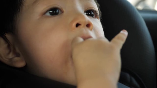 baby boy playing pacifier nipple in car seat