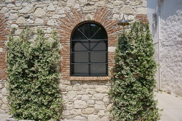 Fototapeta na wymiar Arch shaped iron framed window of a stone brick house