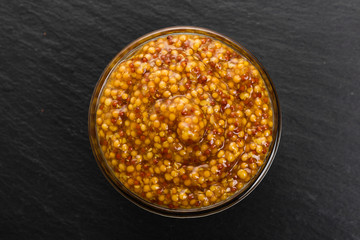 mustard in a bowl on a rustic background