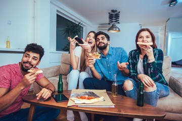 Group of young friends eating pizza and watching tv.Home party.Fast food concept.