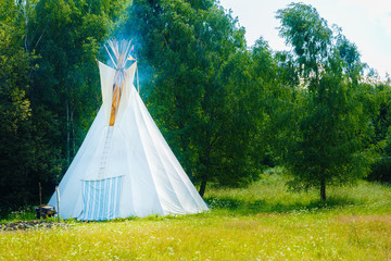 white teepee indian tent standing in beautiful summer landscape. © jozefklopacka