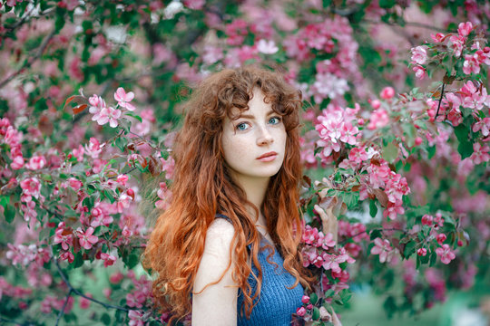 Summer portrait of young tender girl, ginder hair, redhead young girl with freckled skin. Caucasian girl posing in flowers