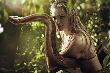 Rolgordijnen Portret van een mooie blonde die een wilde slang vasthoudt © konradbak